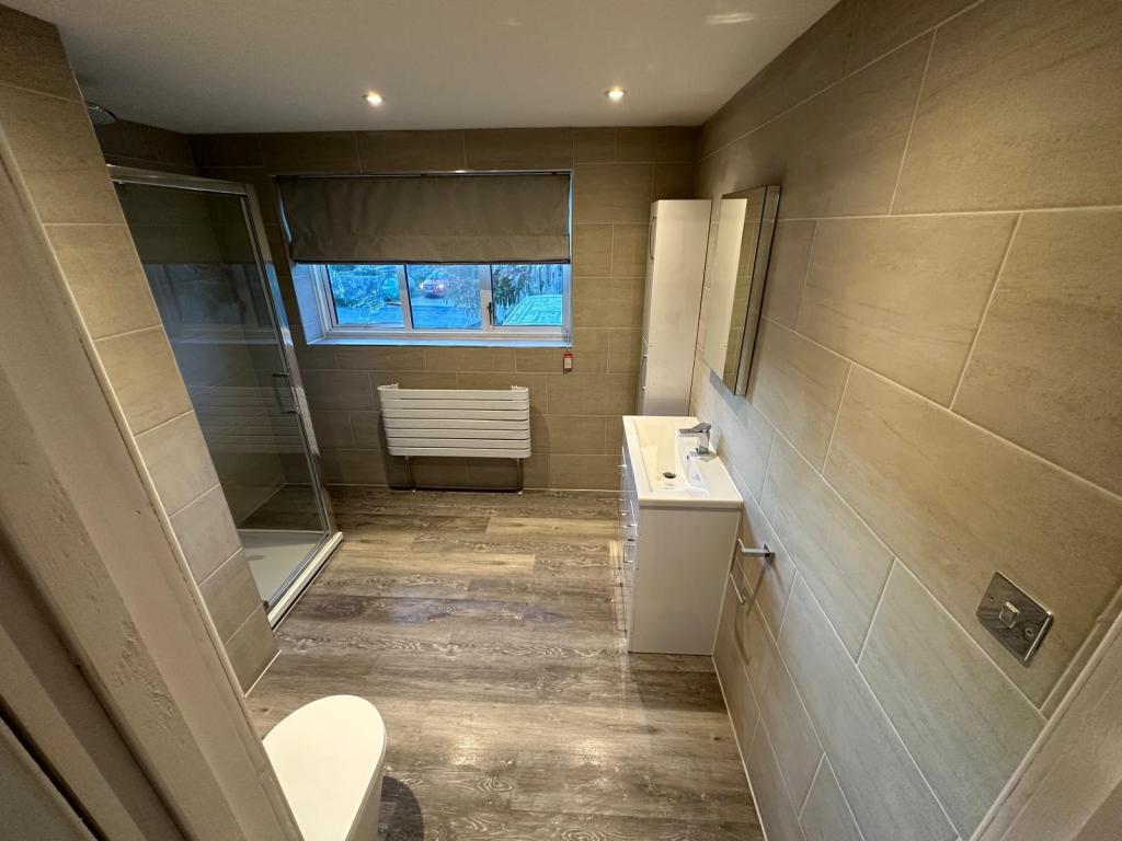 Space-optimised bathroom refurbishment in Oxford with walk-in shower, fitted vanity unit, and full wall tiling